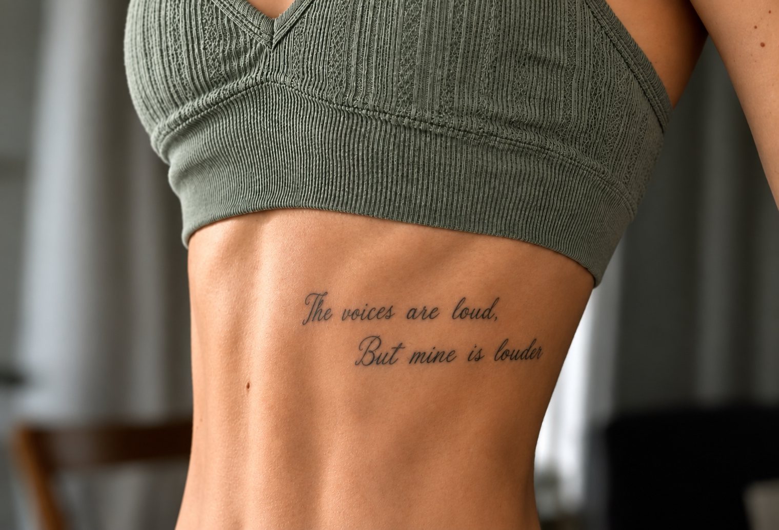 Groene hoodie met tattoo op onderarm: “The voices are loud, But mine is louder”.