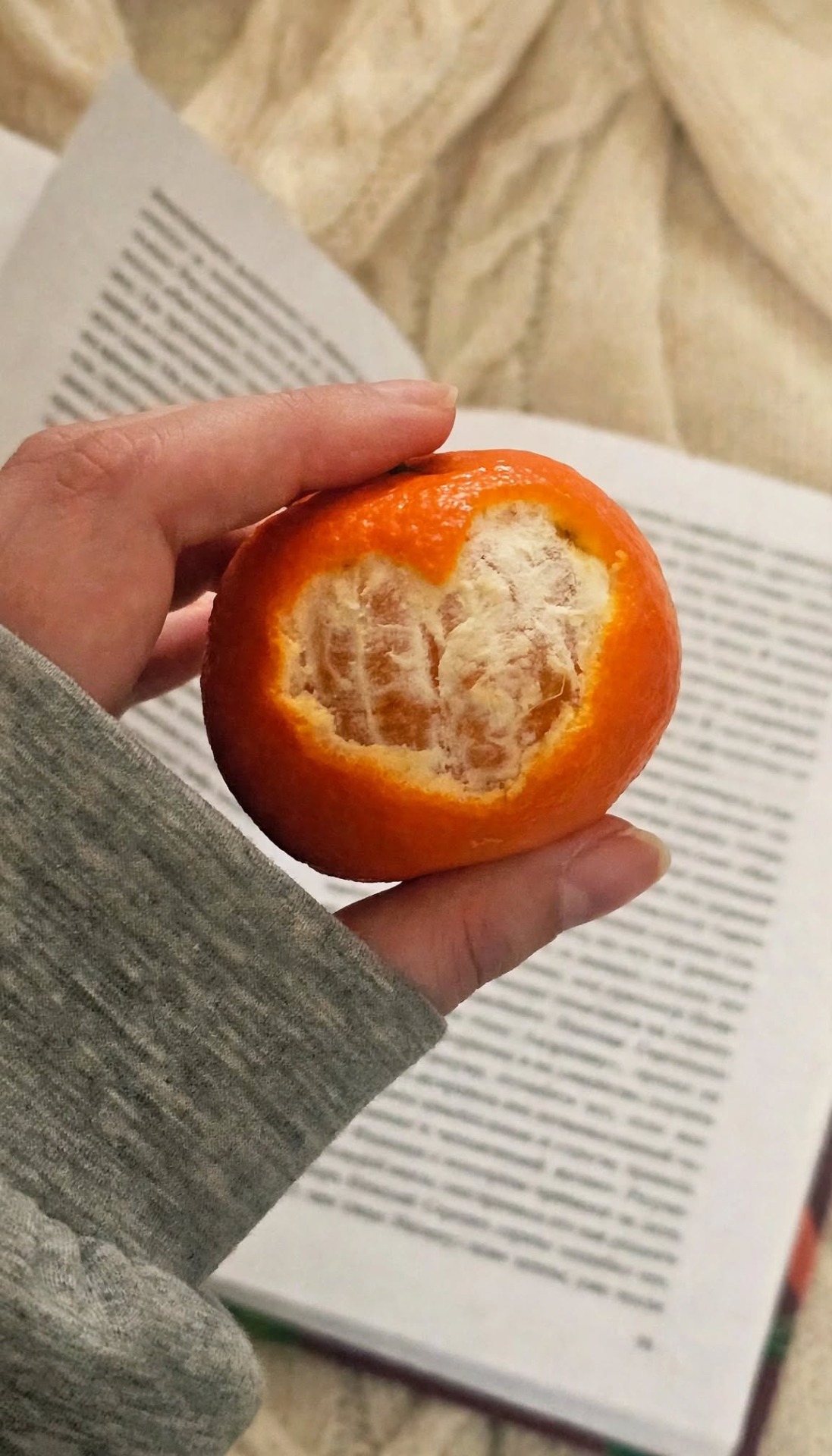 Hand houdt een oranje broodje met zichtbaar wit, gebakken binnenstuk op een gestreepte ondergrond.